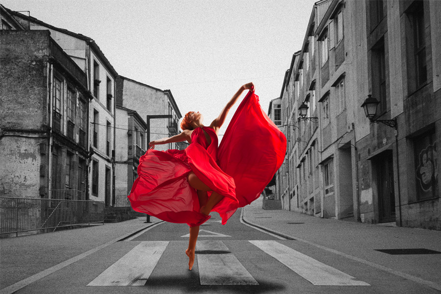 Butschkus Mediendesign: mit zielgerichteter Werbung das digitale Rauschen übertönen. Ein Frau mit einem auffälligen roten Kleid tanzt auf einem Zebrastreifen. Der Straßenzug ist ein einfarbiges Bild in Graustufen.