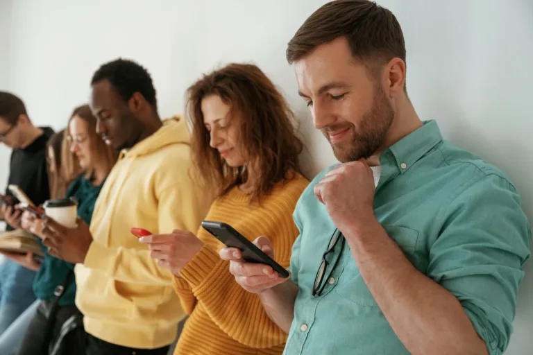 Busy by using smartphones. Group of young people are standing against white background