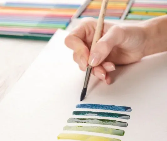 Artist painting colorful stripes with brush on white paper