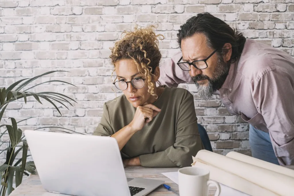 Man and woman working together on laptop in home office at the t
